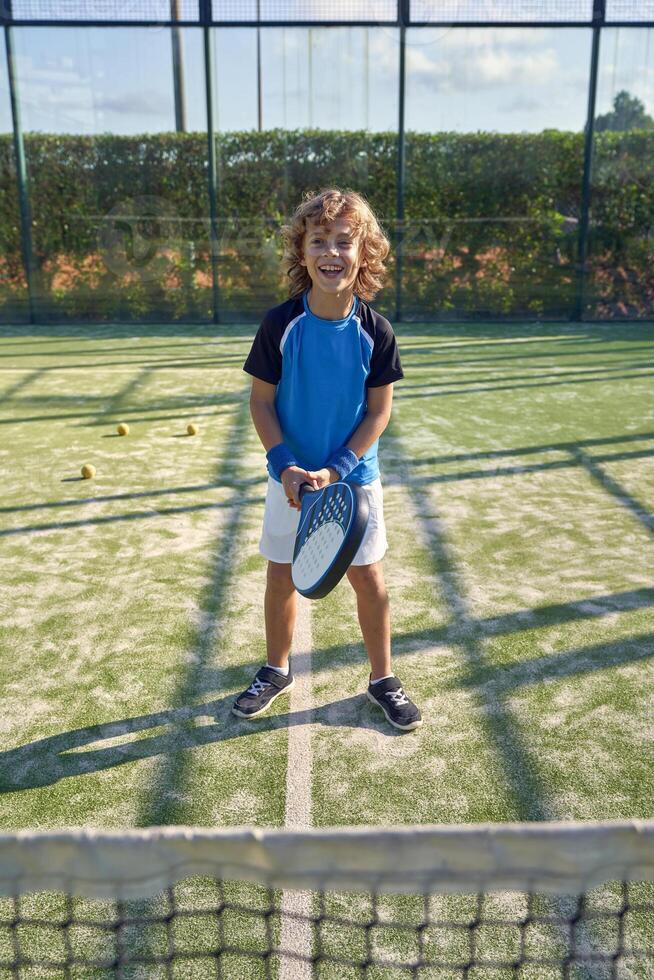 Cheerful boy with racket on playground photo
