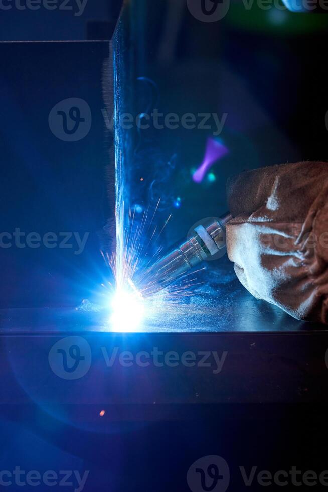 Unrecognizable welder using welding machine in darkness photo