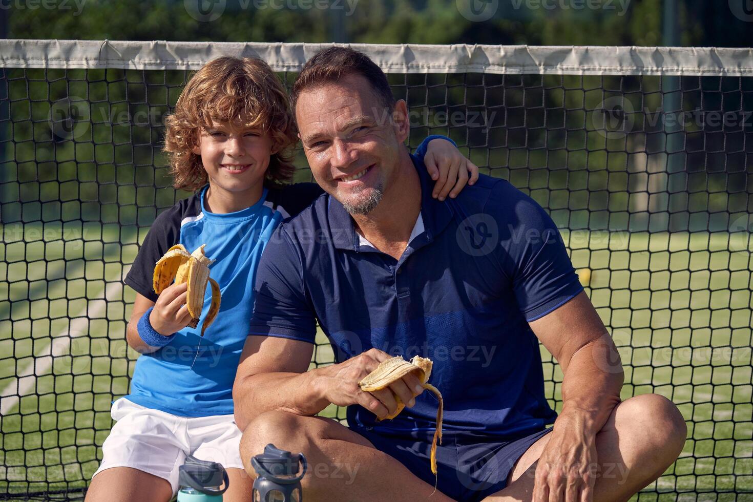 Smiling boy and trainer with bananas on court photo