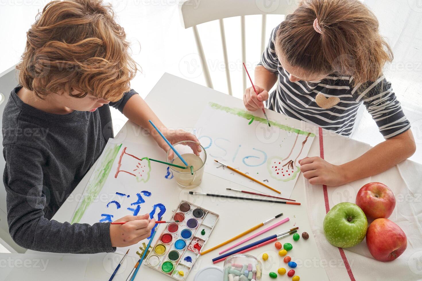 Children drawing on paper sitting at table photo