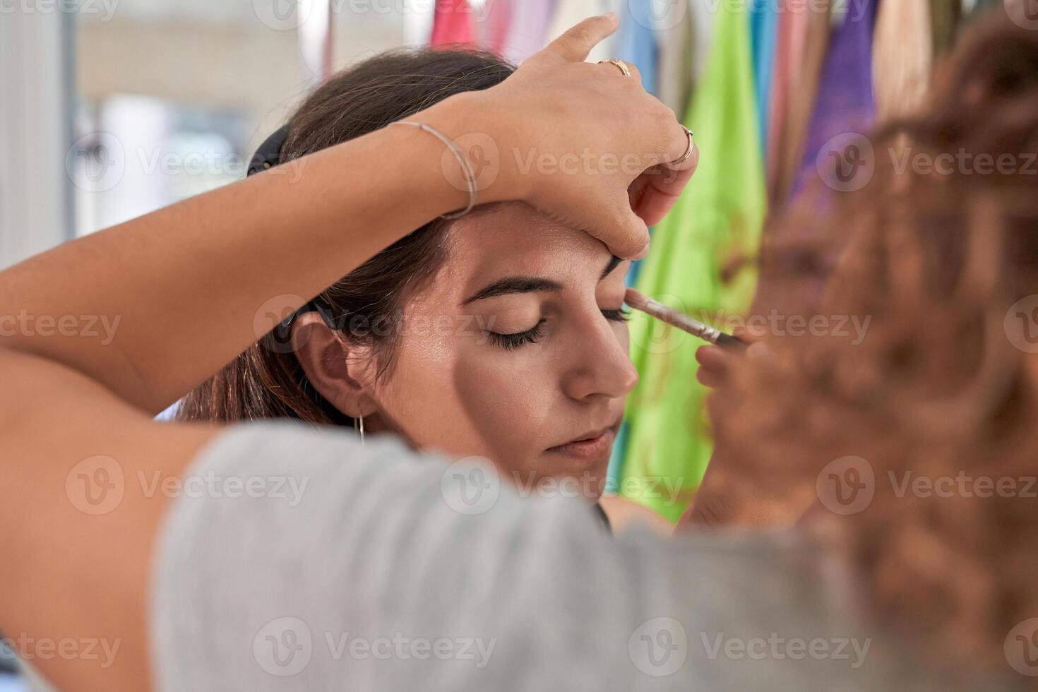 Unrecognizable woman applying eyeshadow on model photo