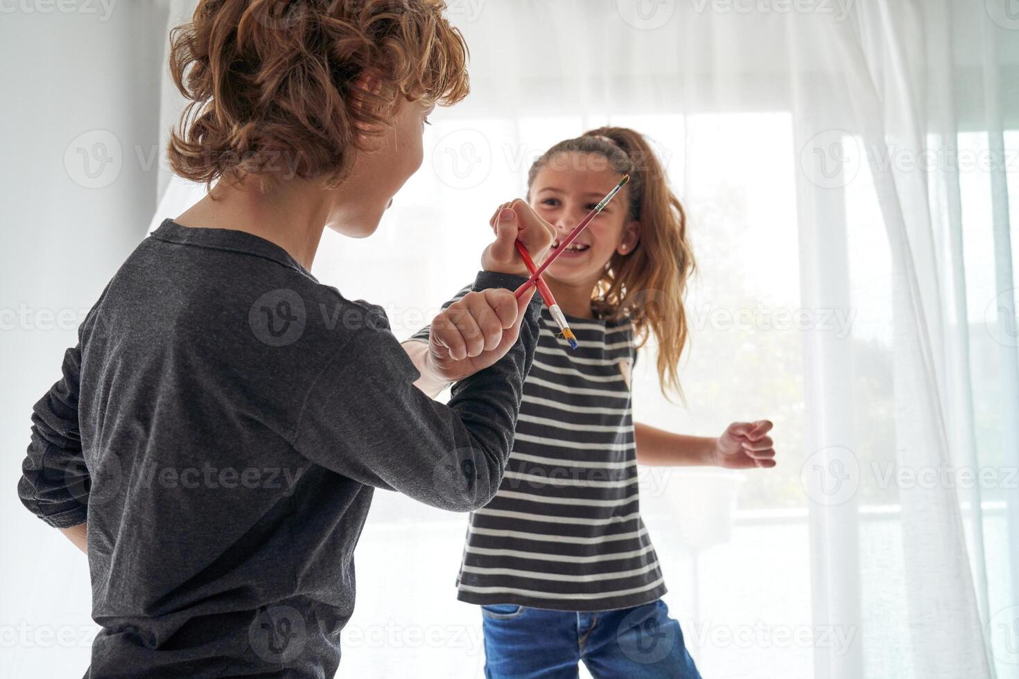 Boy and girl playing with paintbrushes photo
