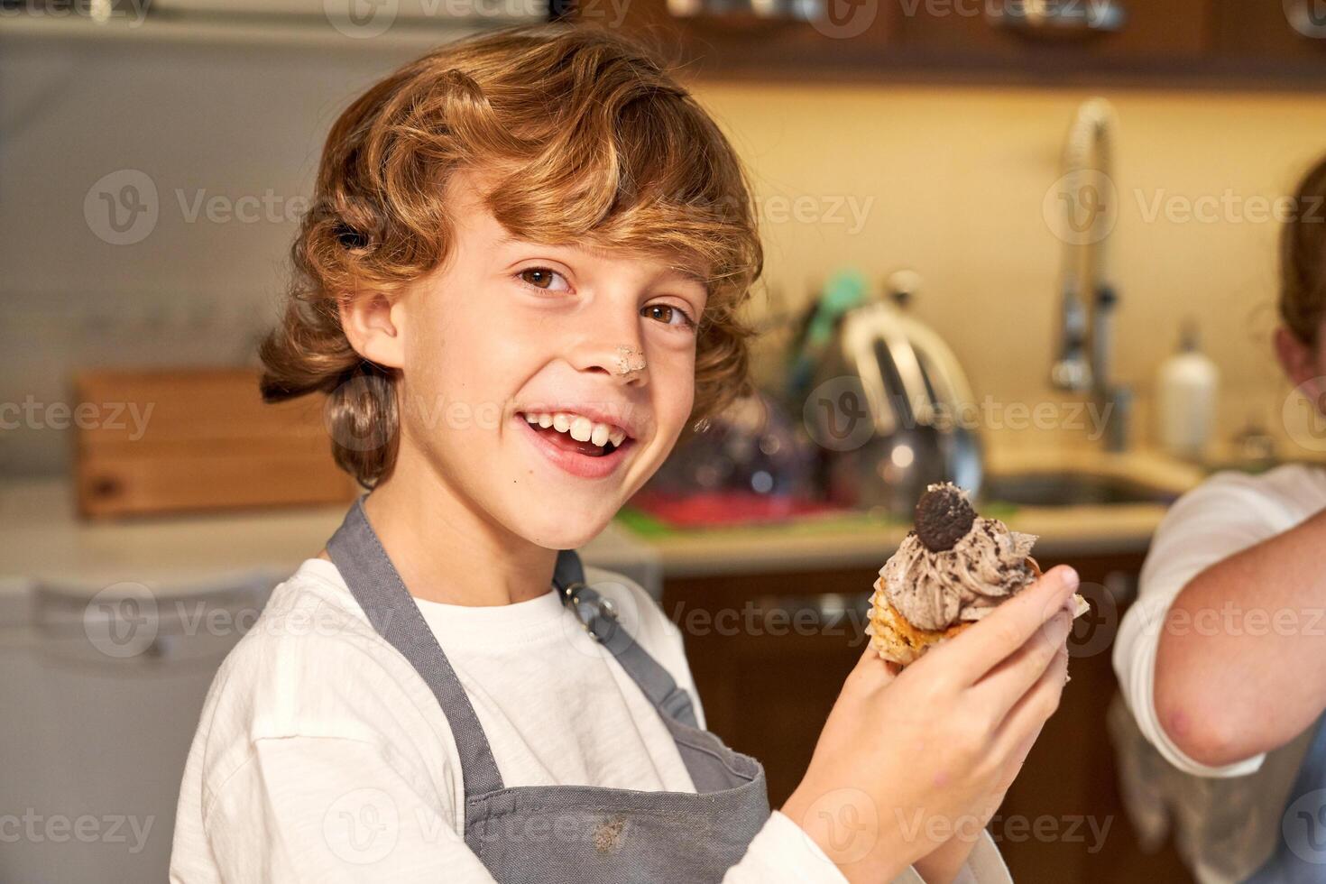 Smiling boy with homemade cupcake in paper baking tin photo