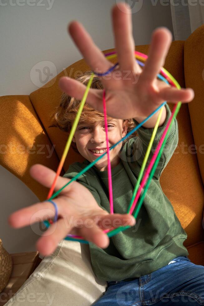 Delightful boy with multicolored strings on fingers photo