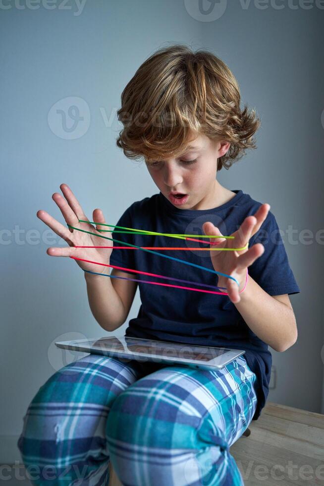 Astonished boy playing string game with tablet photo