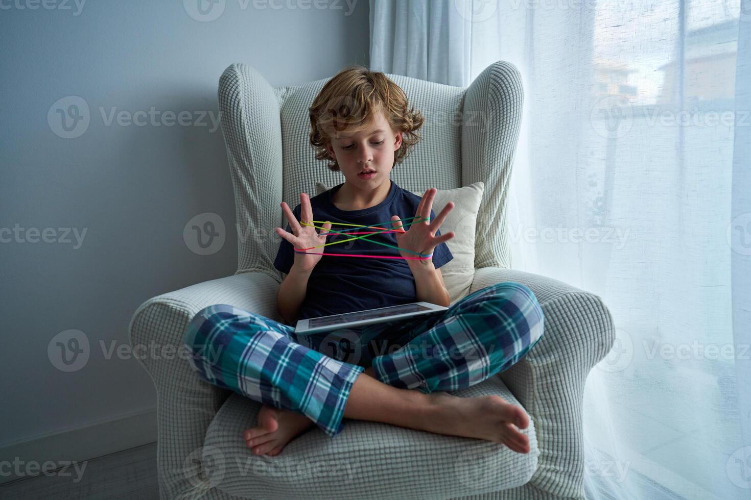 Concentrated boy playing cats cradle game in room photo