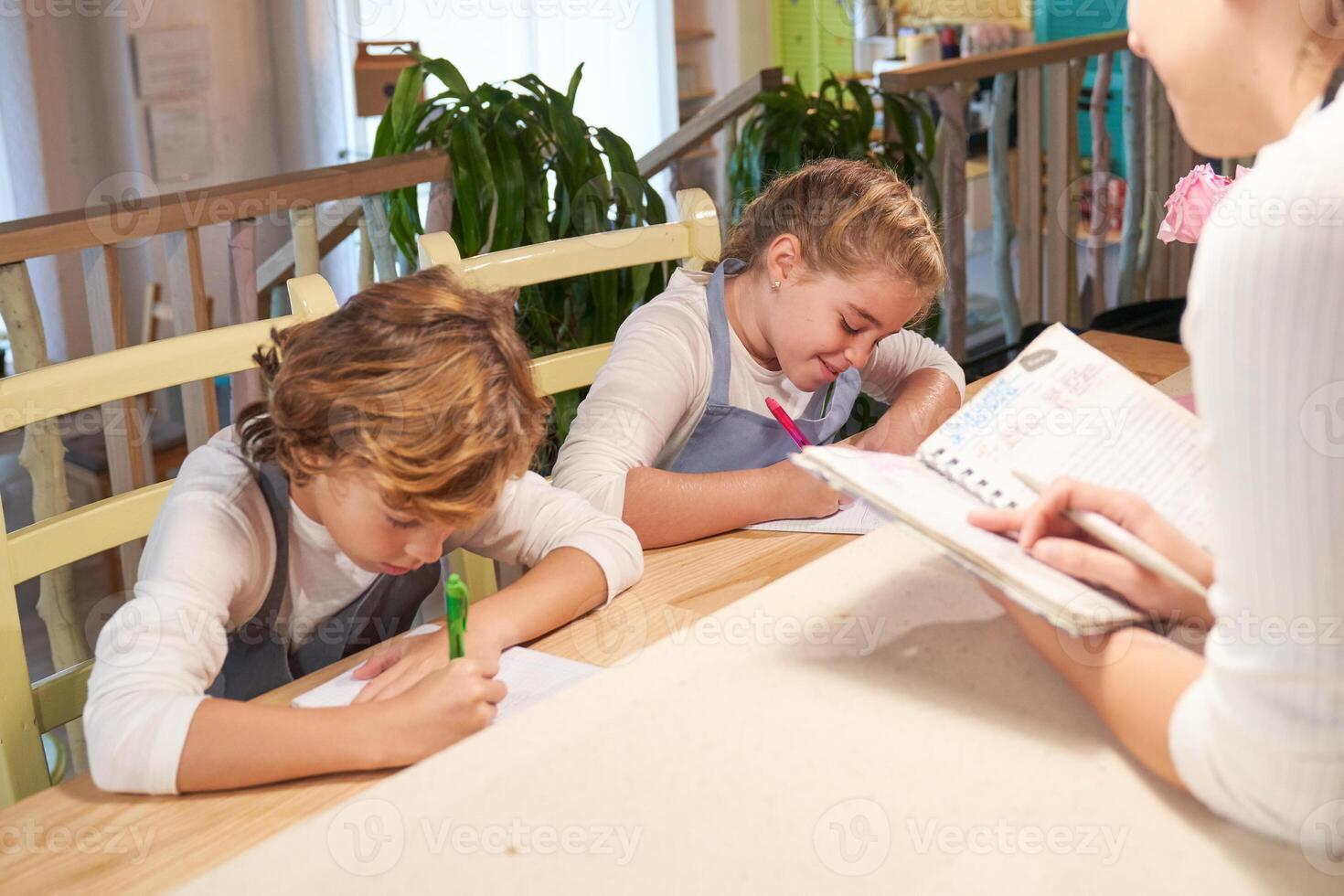 Crop mom dictating for children sitting at table and doing homew photo