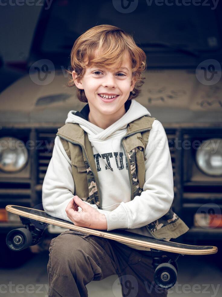 Smiling kid with skateboard on street photo
