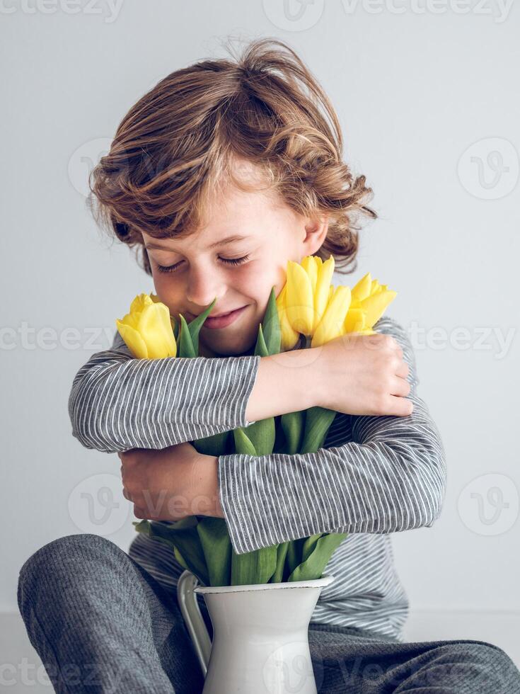 Content boy hugging bouquet of tulips photo