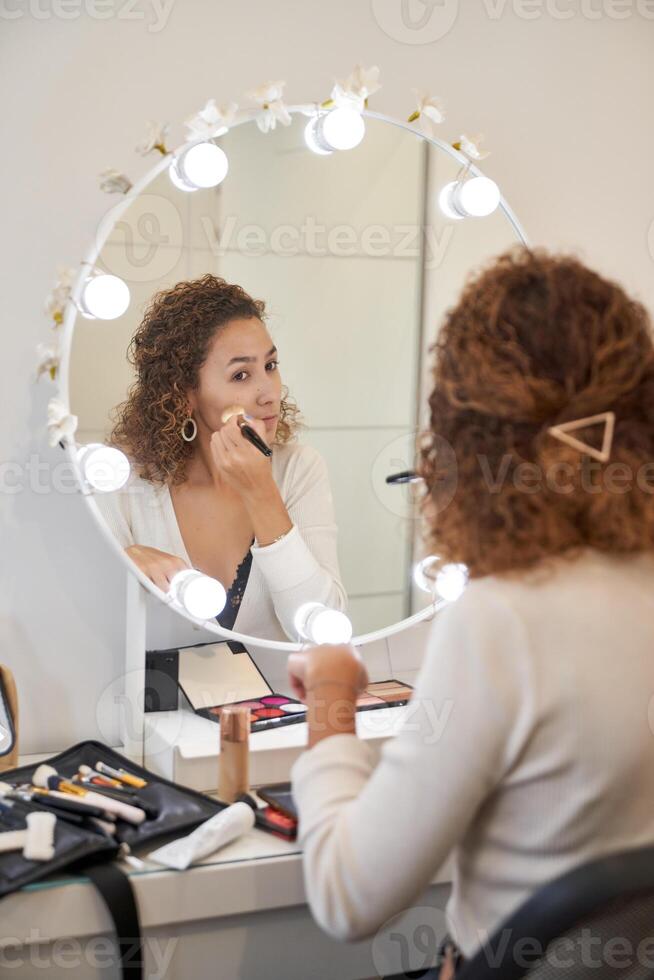 Woman applying makeup near mirror photo