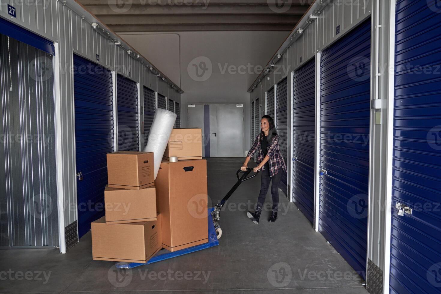 Woman rolling carton boxes into storage photo