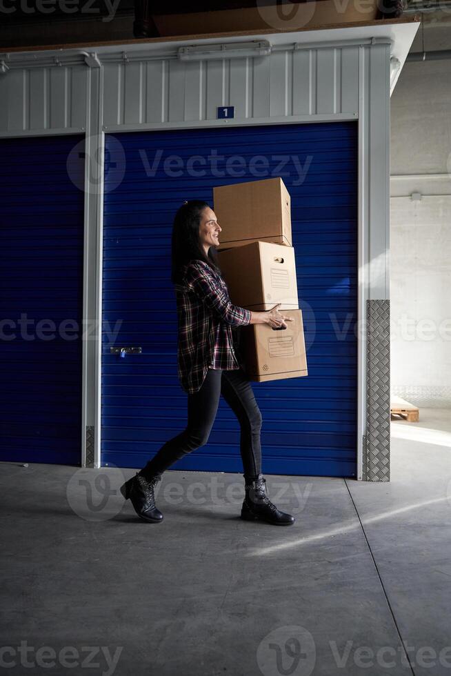 Woman carrying packing boxes near storage photo