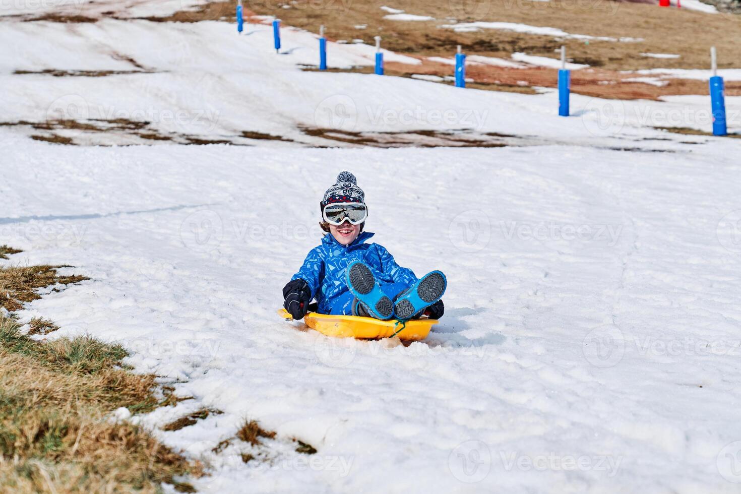 Positive boy sliding down snowy slope photo