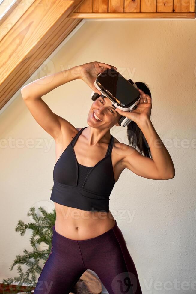 Positive slim woman doing exercises in VR glasses photo