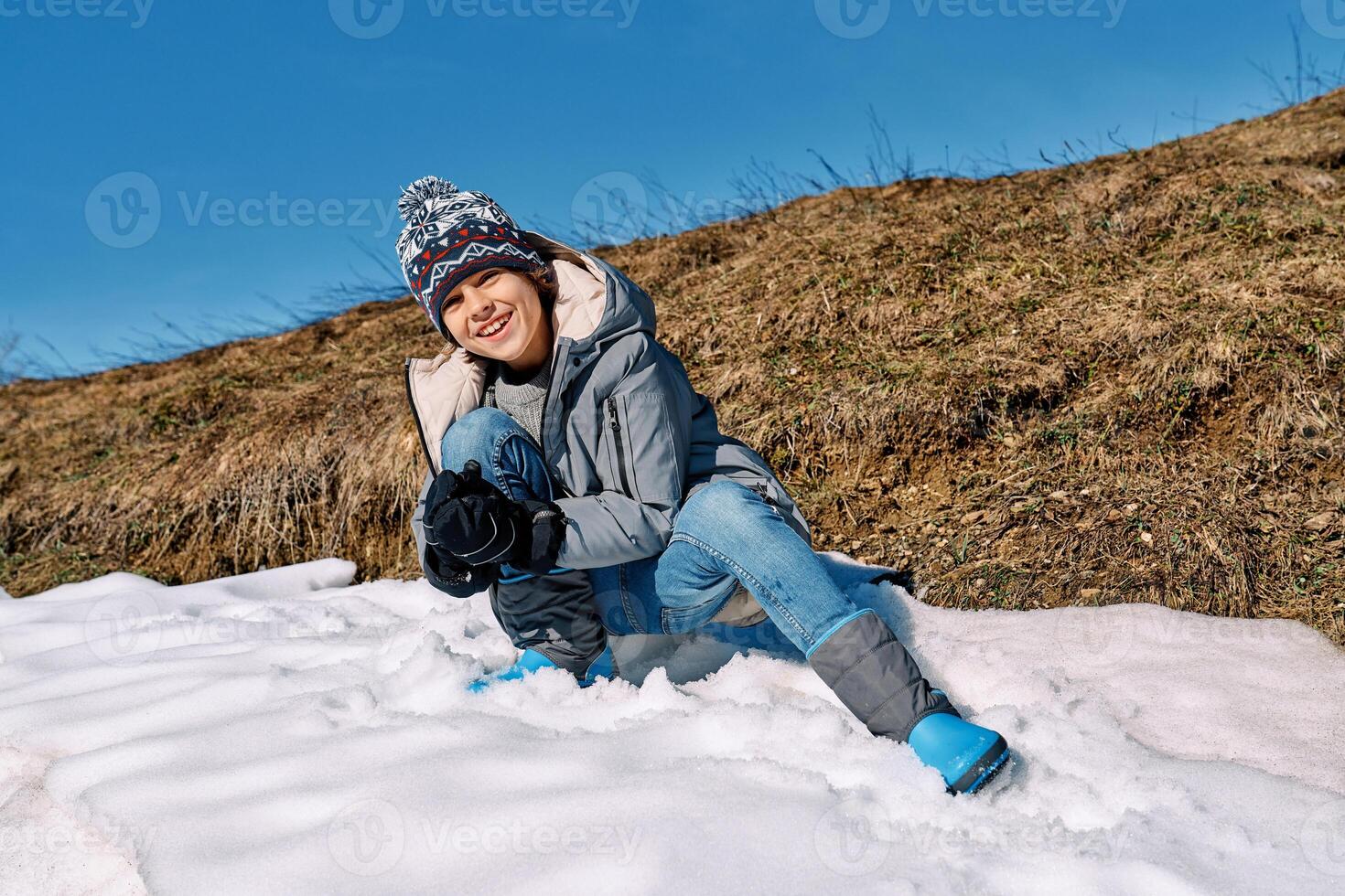 Cheerful boy making snowball in nature photo