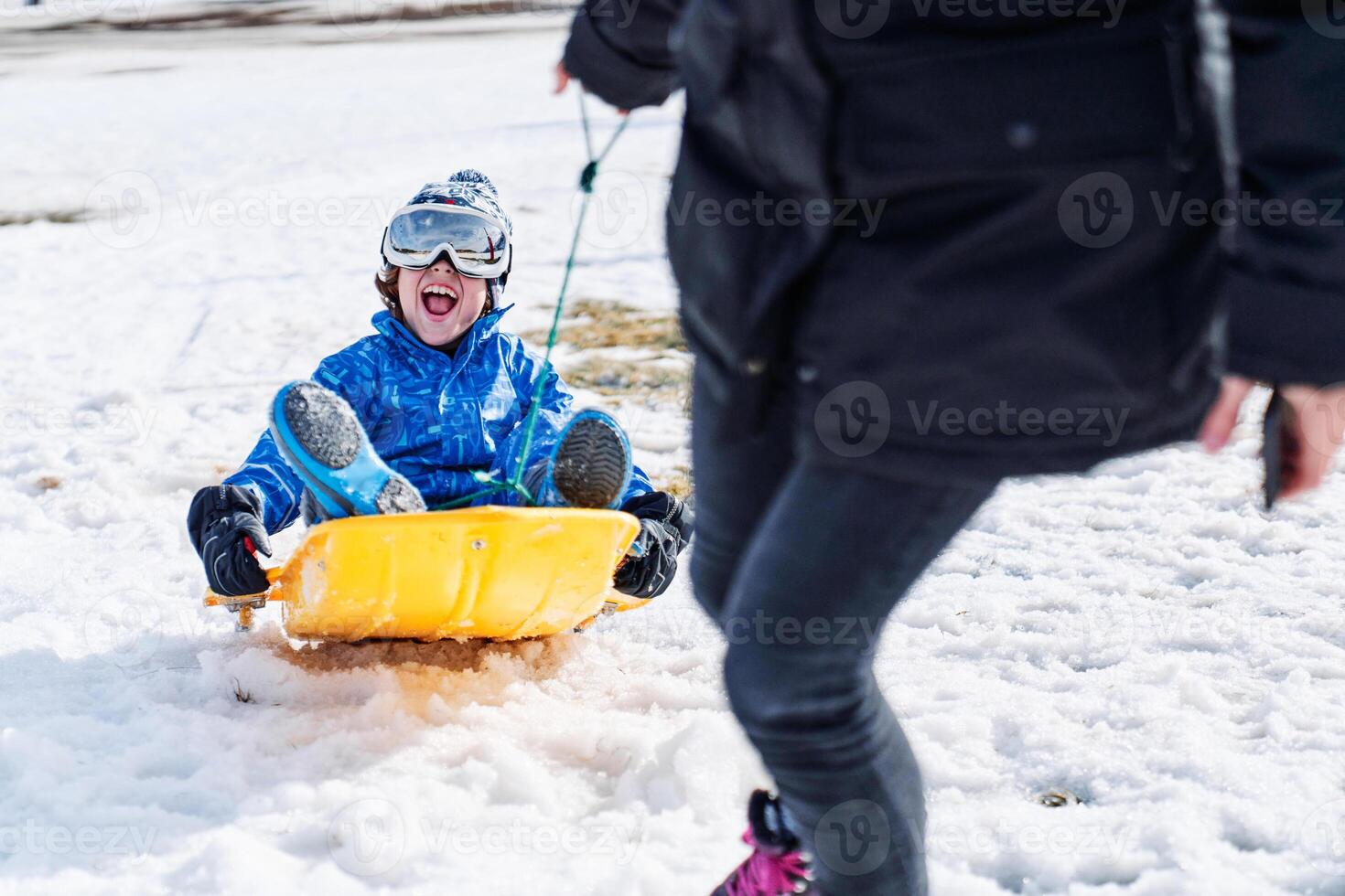 Excited son riding sledge near mother photo