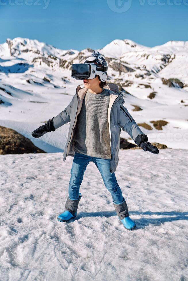 Boy playing VR game near snowy hills photo