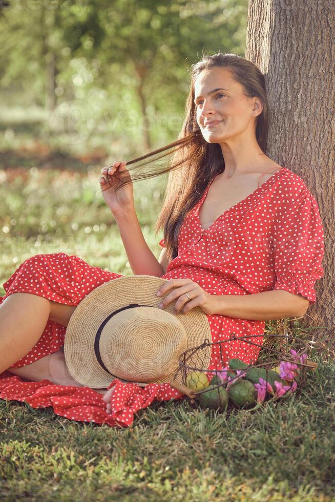 Young woman with hat sitting on grass photo