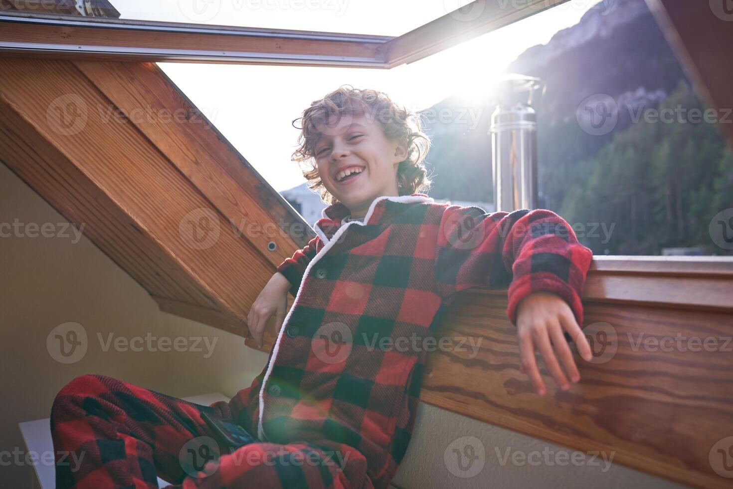 Cheerful boy sitting near open window photo