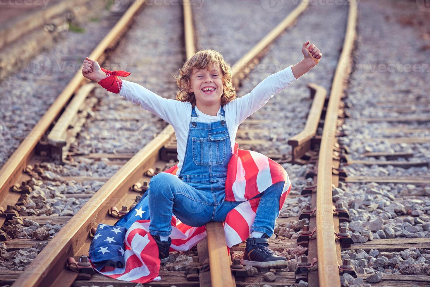 Happy boy with American flag on railroad photo