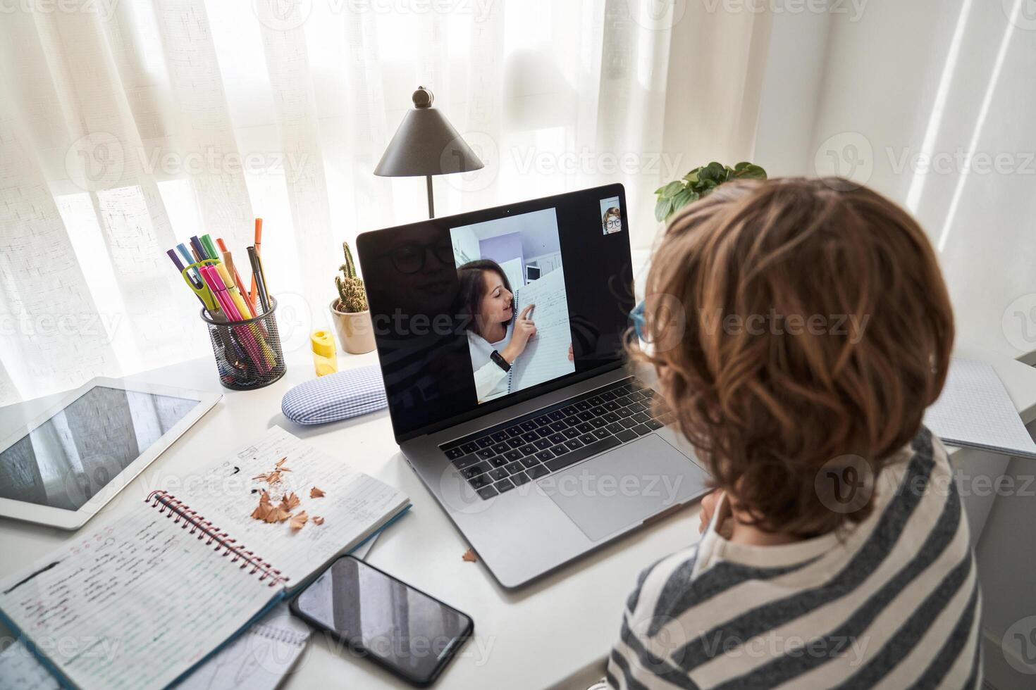 Faceless boy doing schoolwork with girl via laptop photo