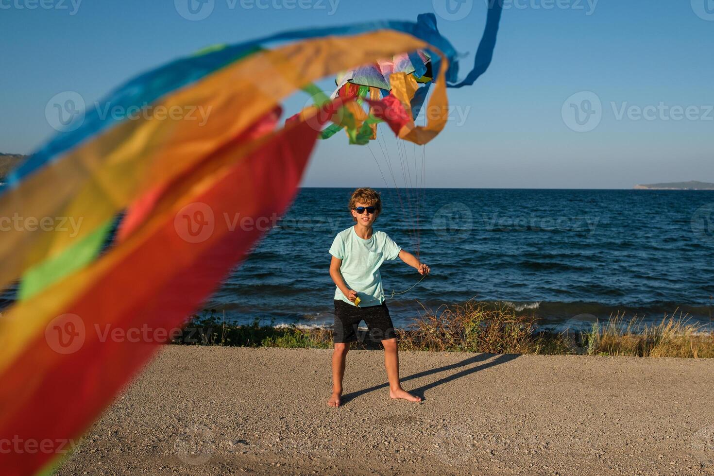 Carefree boy with fluttering kite on beach photo