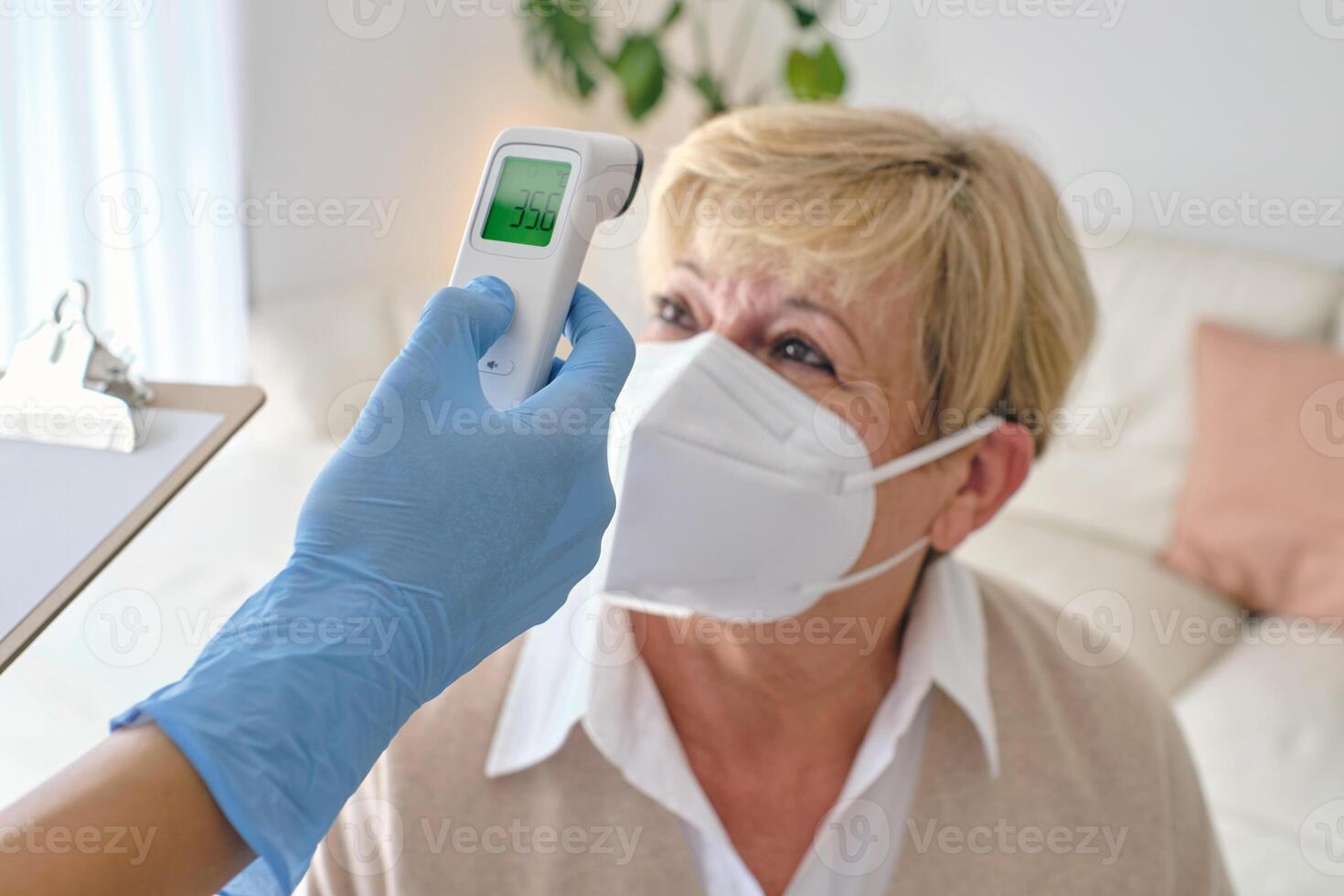 Crop physician measuring temperature of patient with infrared th photo