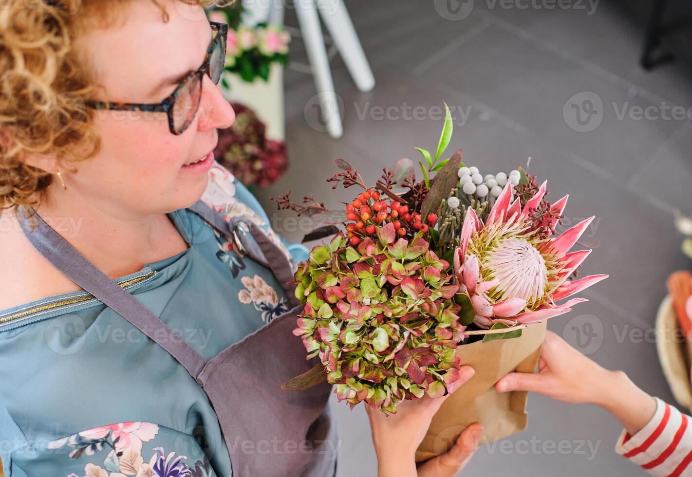 Female florist in eyeglasses selling flowers to client photo