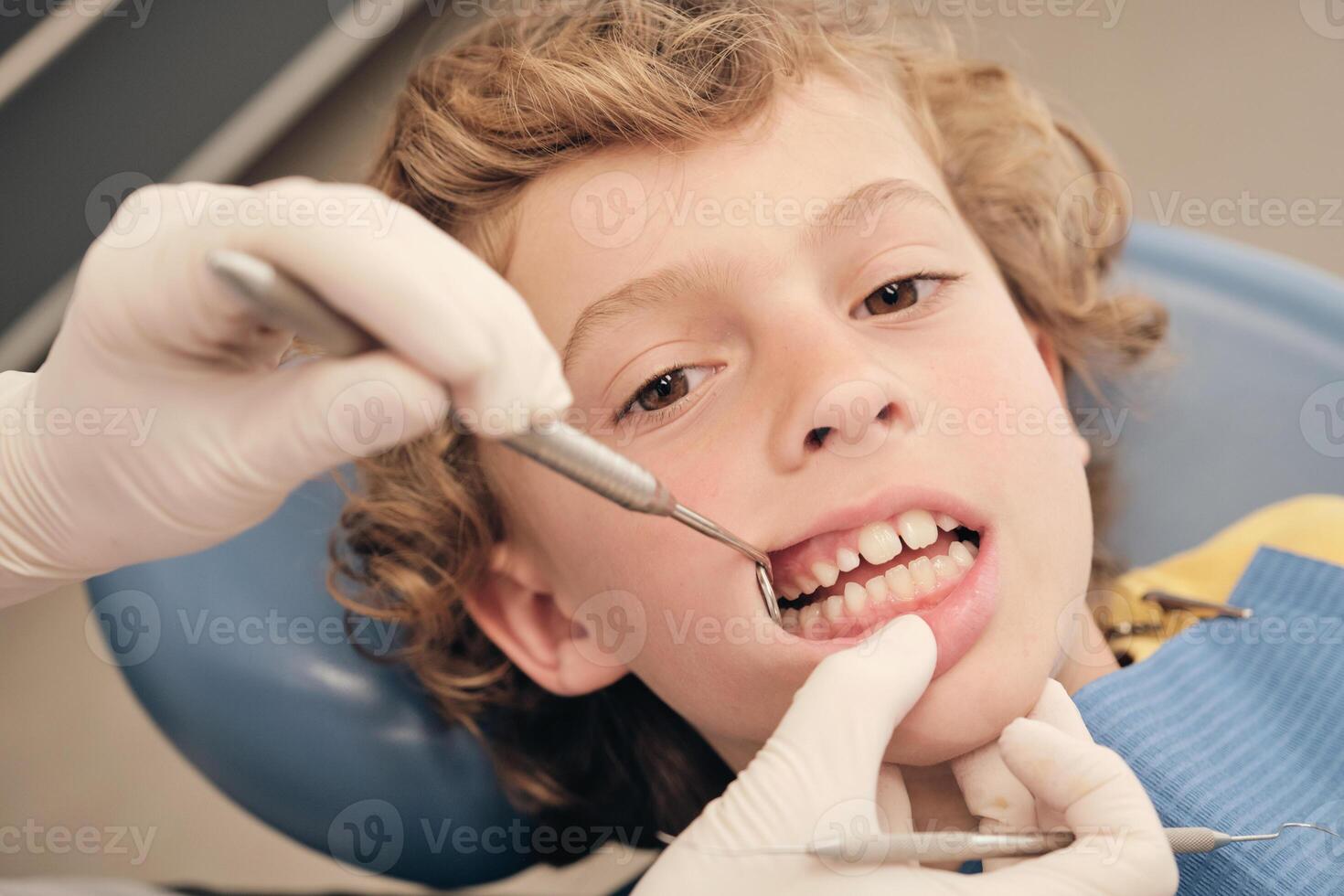 Faceless dentist checking teeth of boy photo