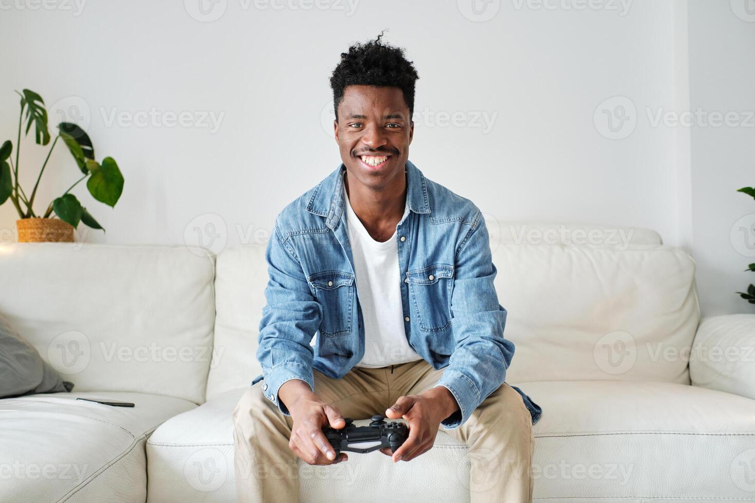 Happy black man with joystick sitting on sofa photo