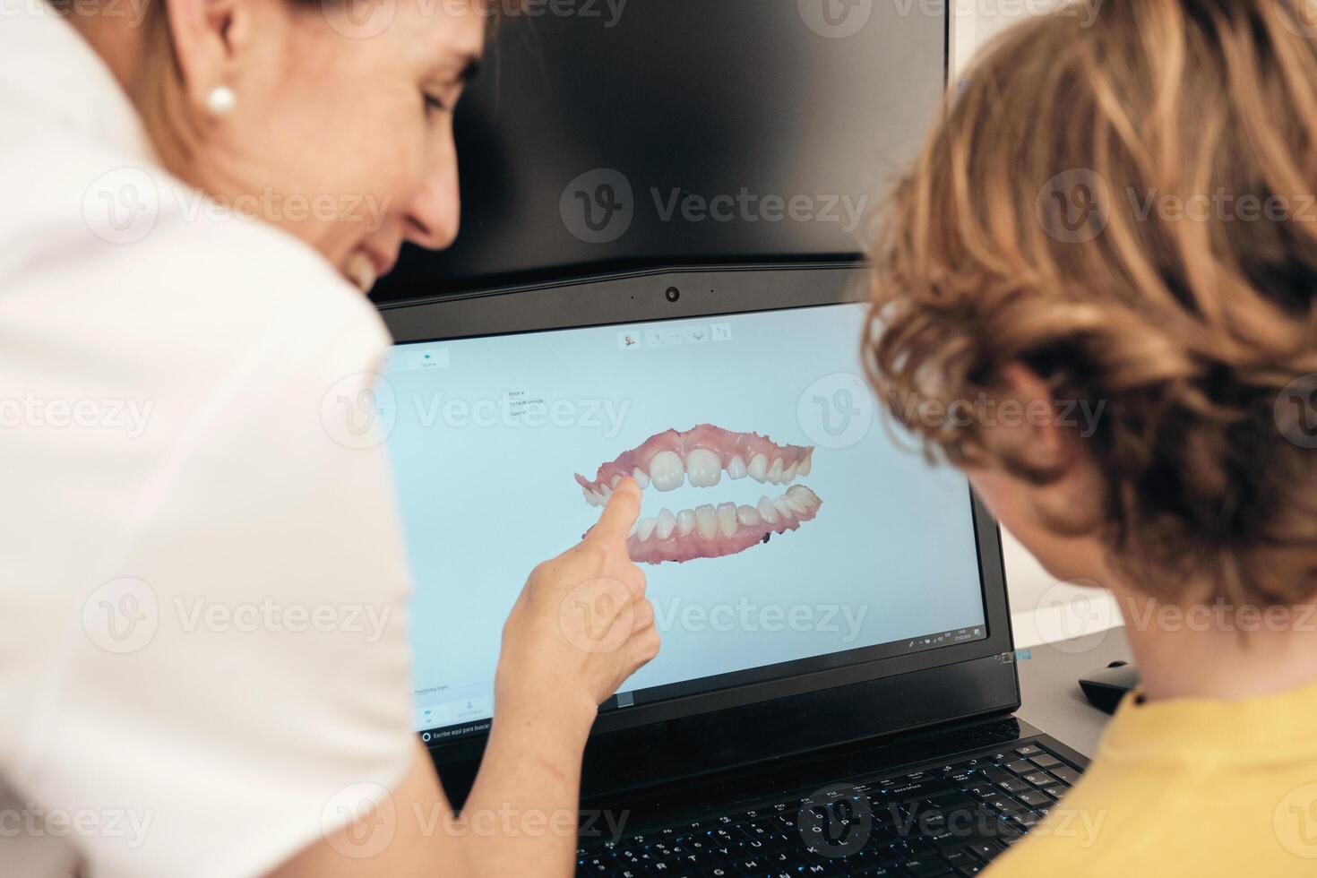 Dentist showing 3D teeth scan to faceless boy photo