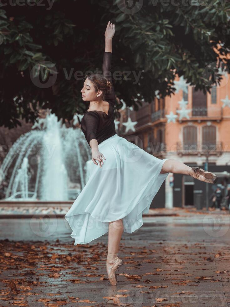 Gracious ballerina performing arabesque position in park photo