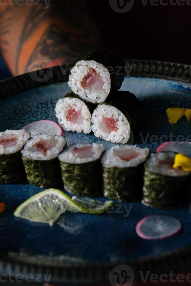 Anonymous waiter with delicious sushi rolls with salmon on tray photo