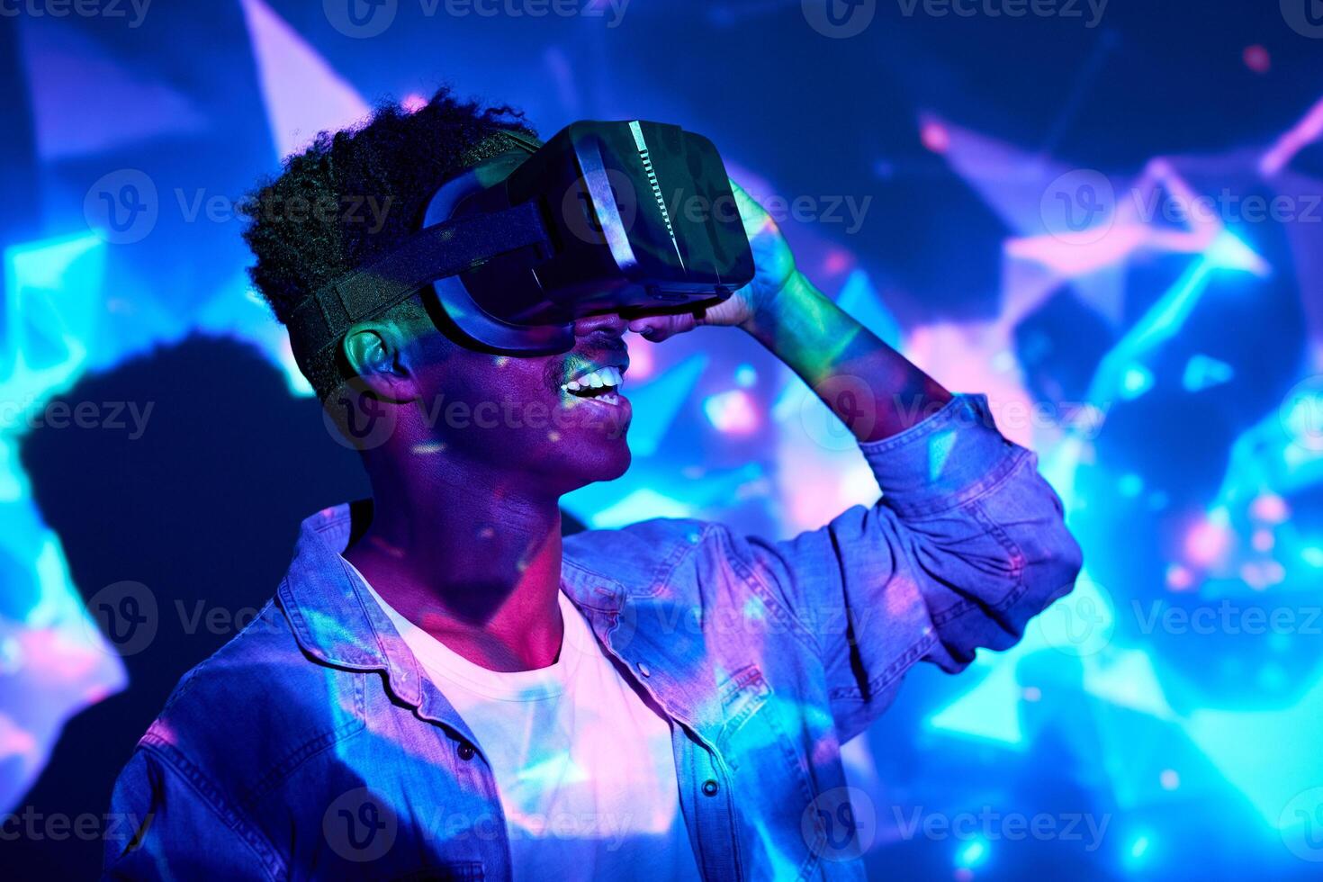 Expressive black man in VR headset in neon lights photo