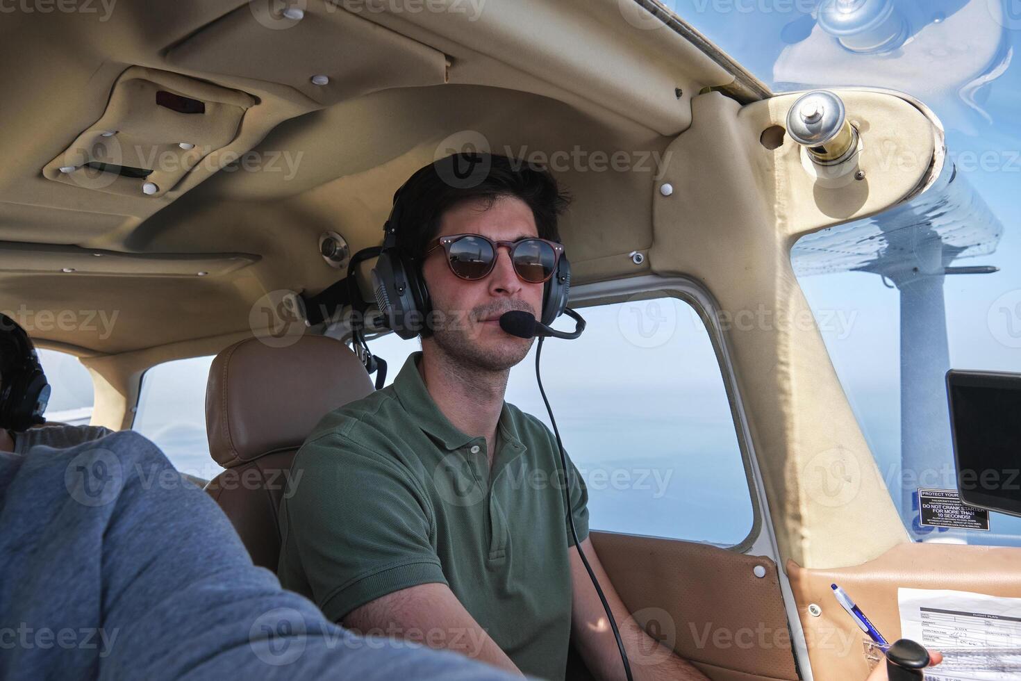 Serious male pilot flying airplane in blue skies photo