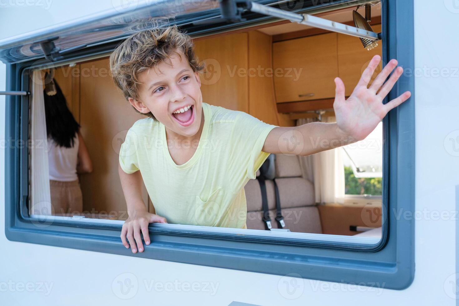 Happy boy waving hand from RV window photo