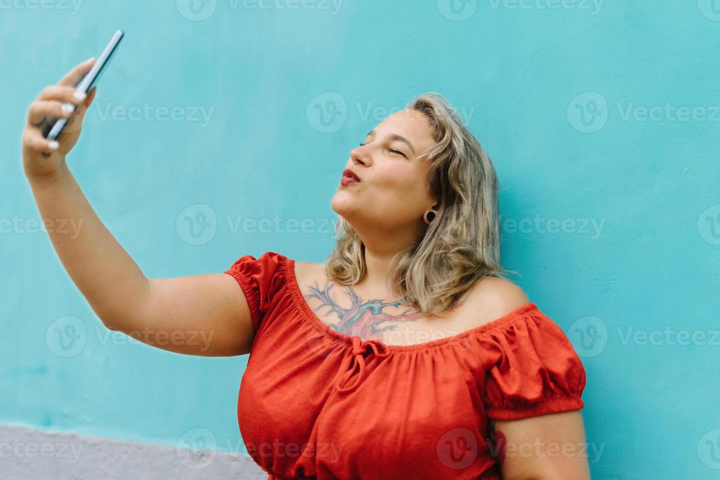 Young plump woman with round mouth pose taking selfie on smartphone photo