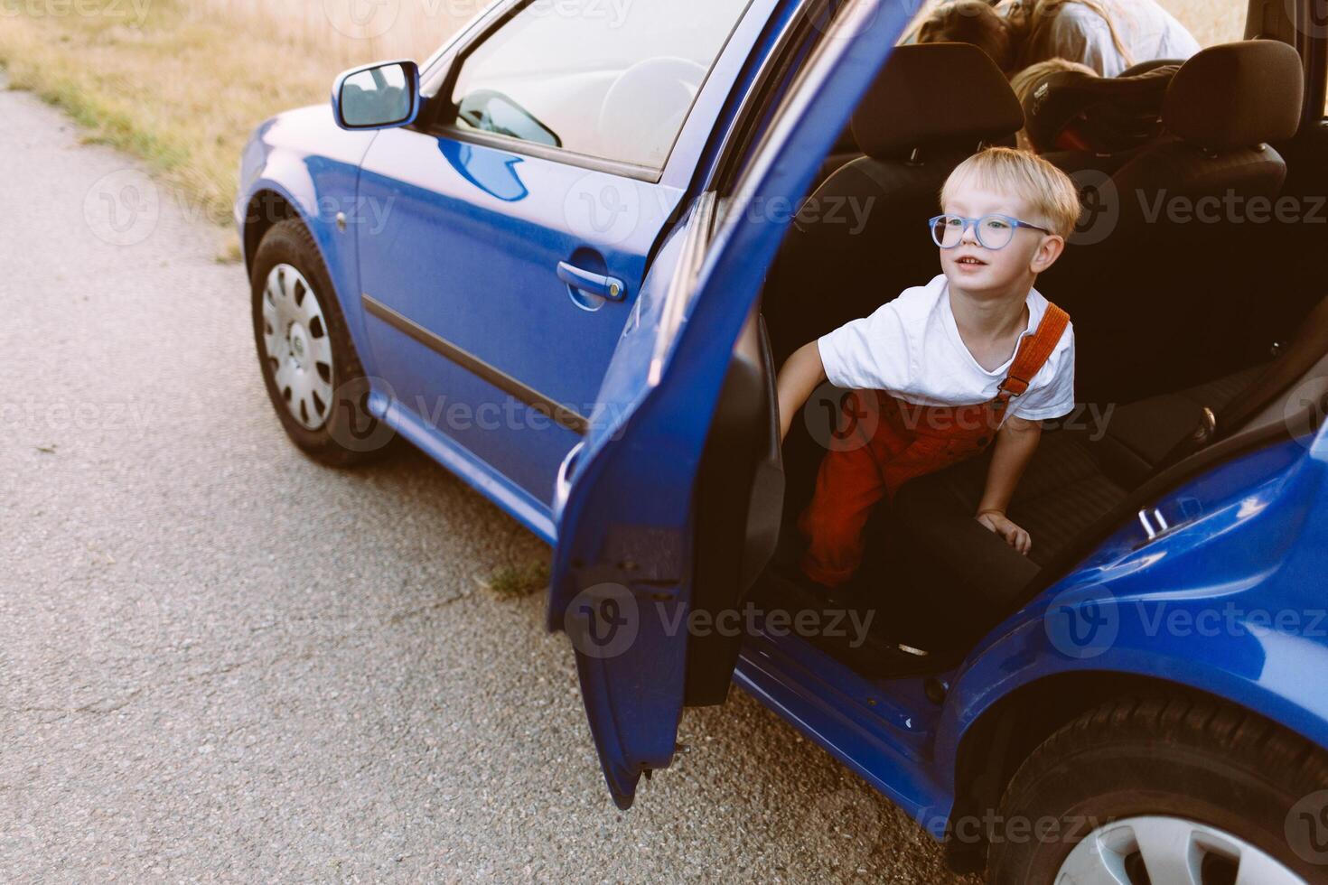 Happy little child in blue car park on asphalt road in countryside photo