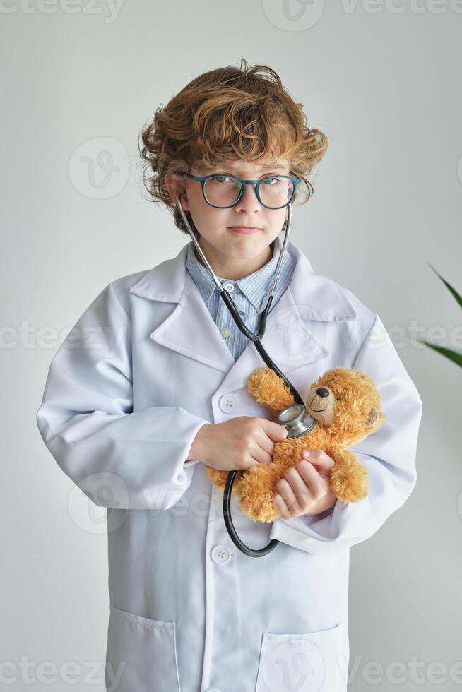 Boy doctor with stethoscope and toy bear during checkup photo