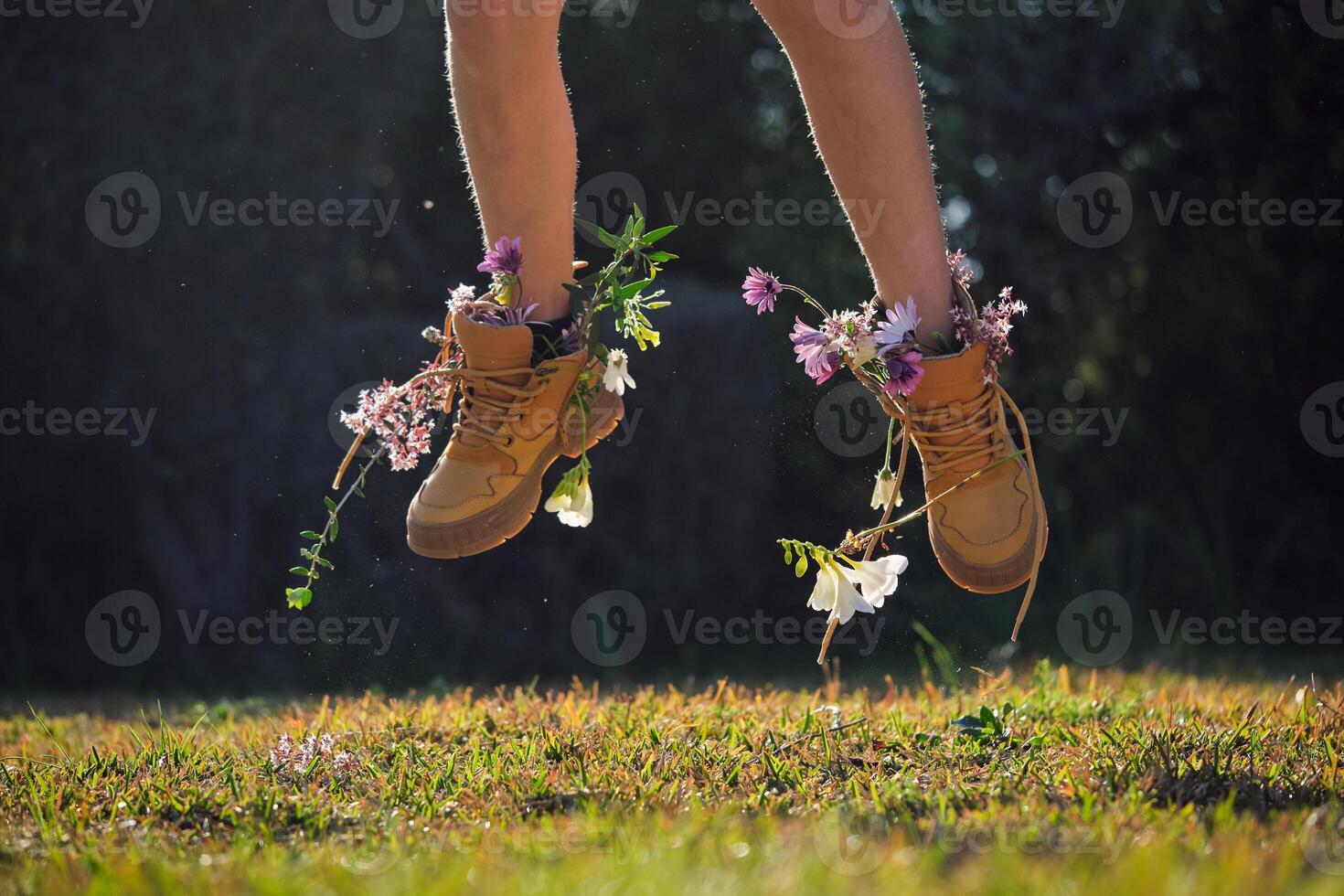 Crop person in boots with flowers jumping in nature photo