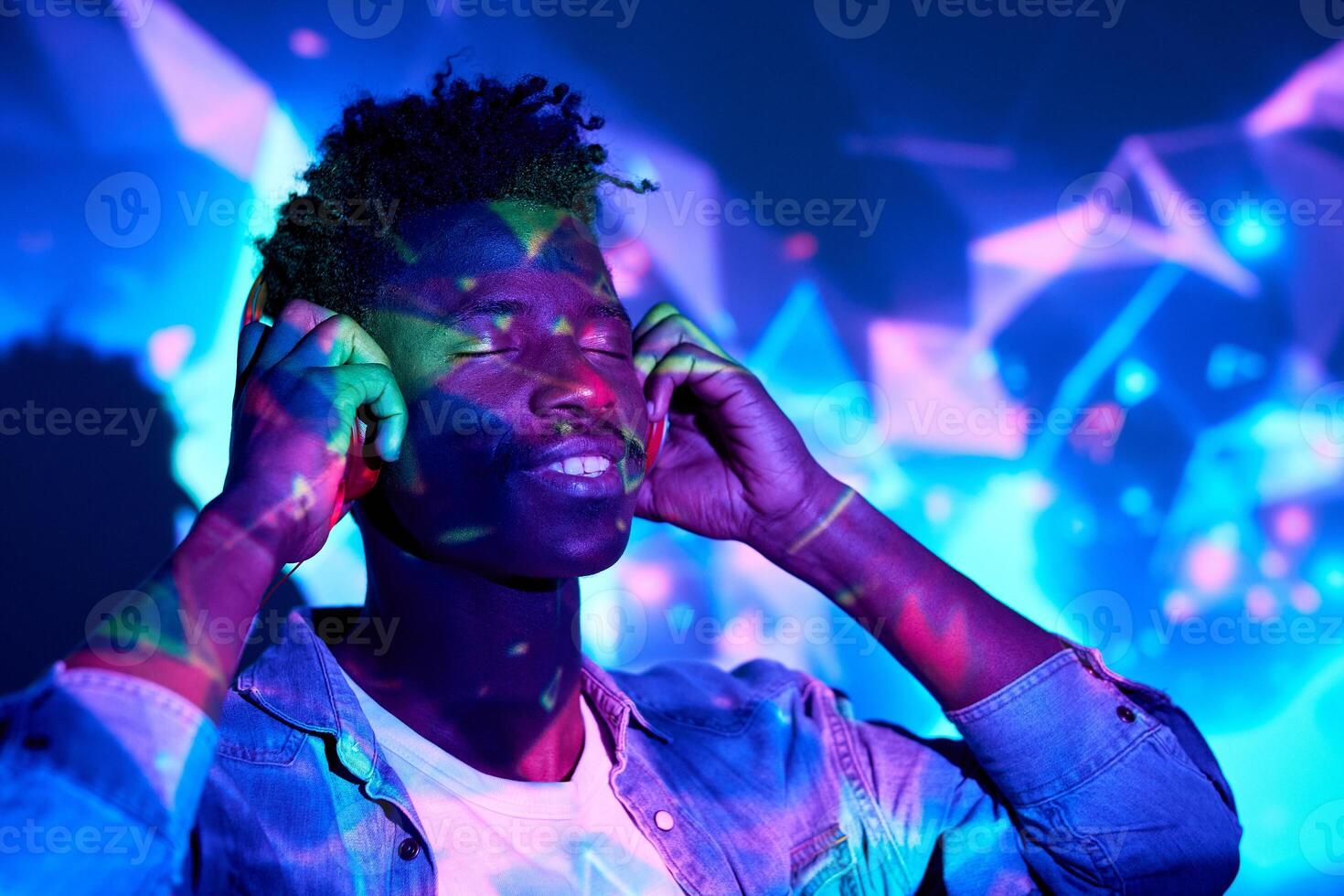 Smiling black man listening to music in headphones in studio photo