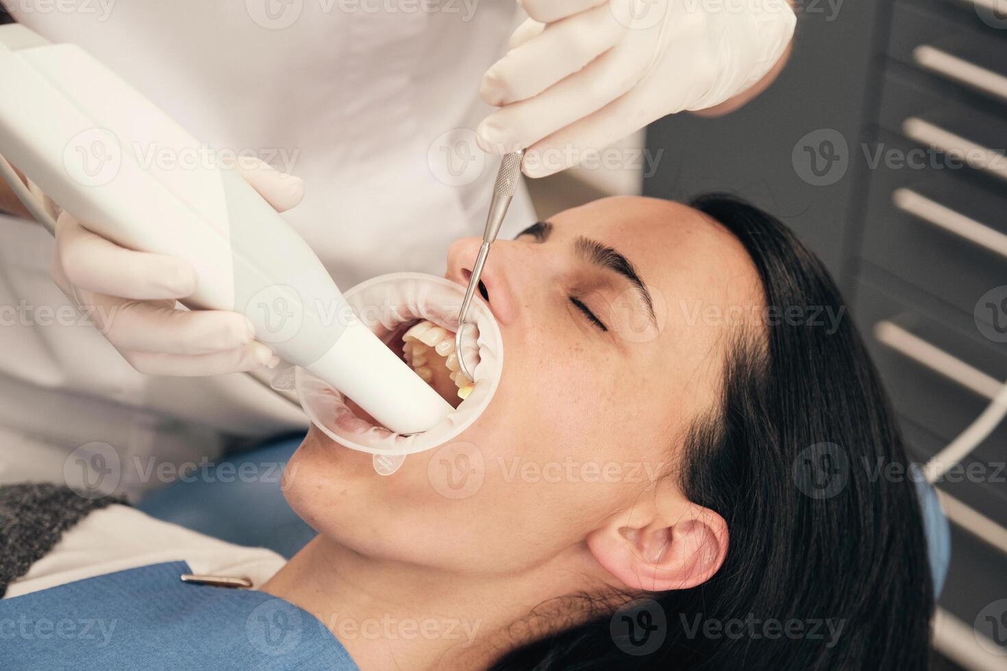 Crop stomatologist working with client teeth during 3D scanning photo