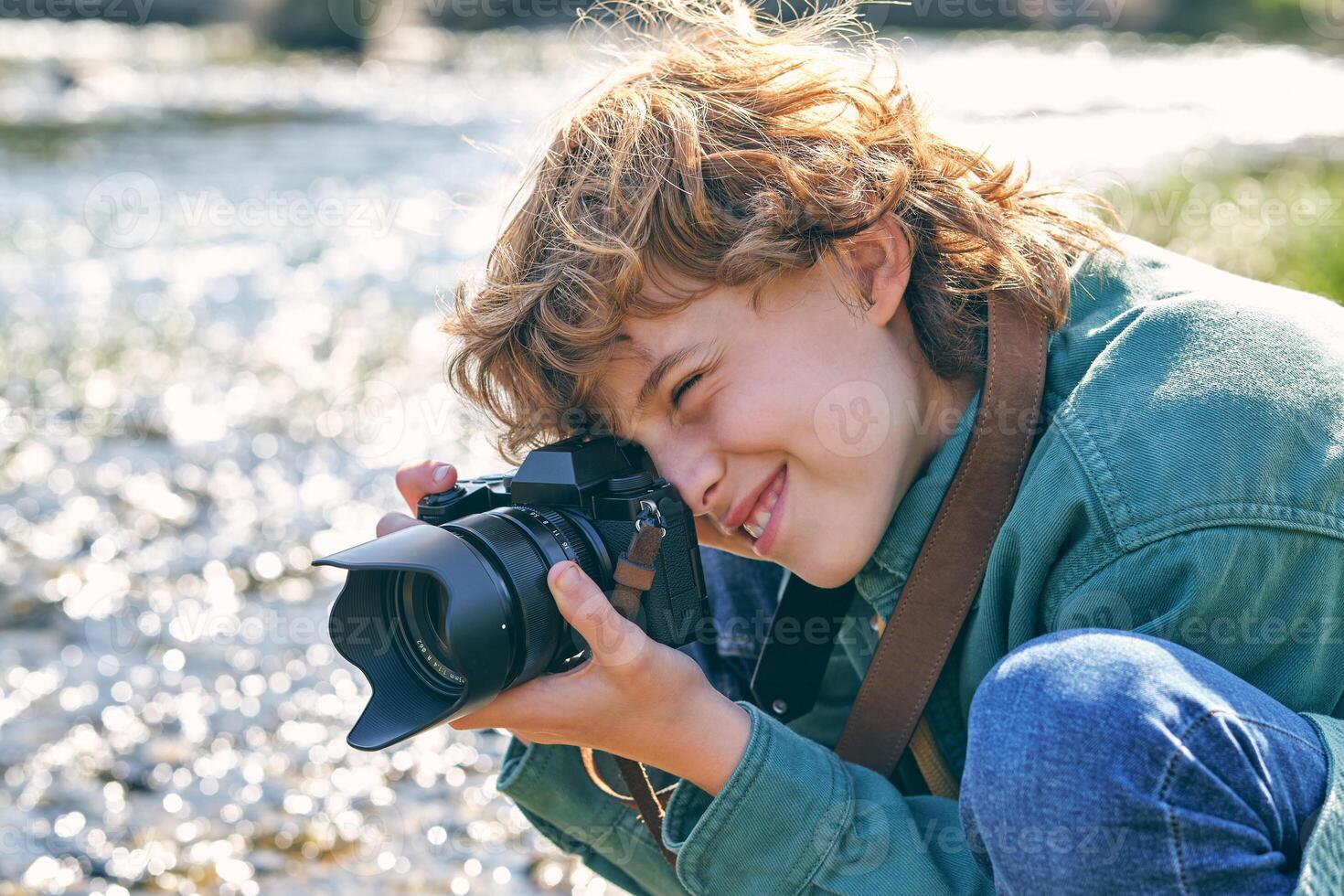 Cheerful boy taking photo on grassy coast