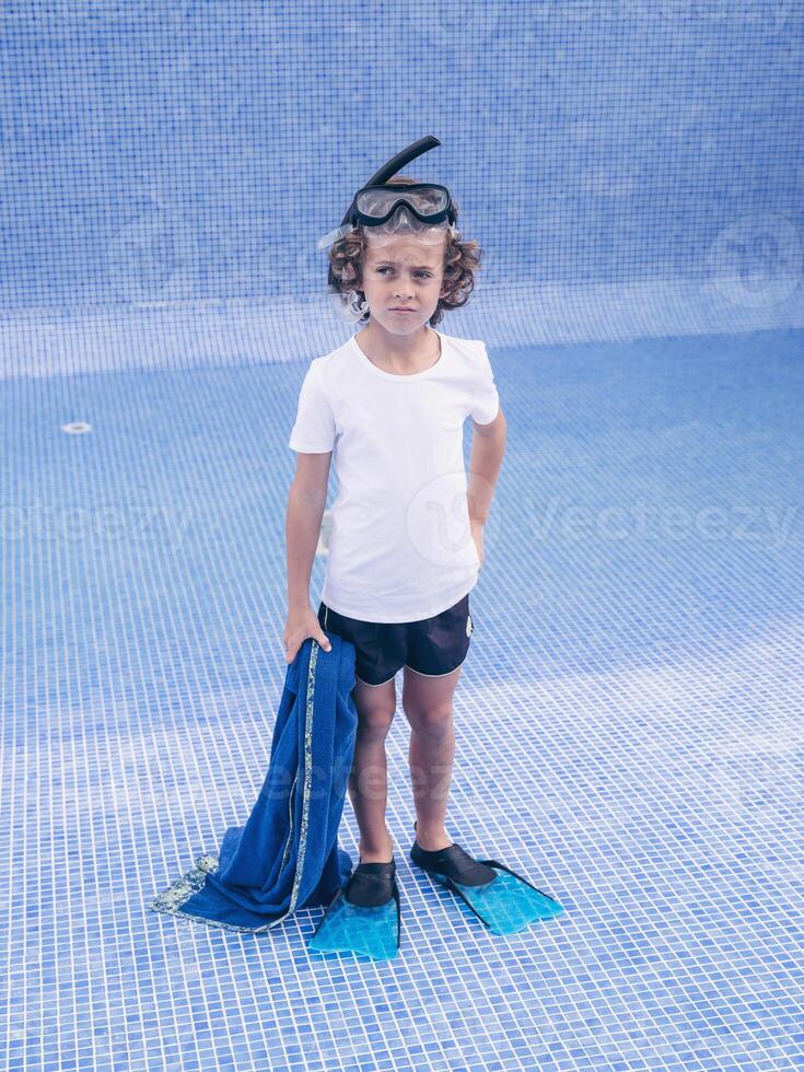 Discontent preteen bot in diving mask and flippers on pool photo