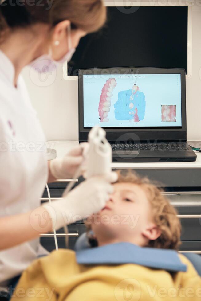 Unrecognizable dentist making 3D teeth scanning of boy photo