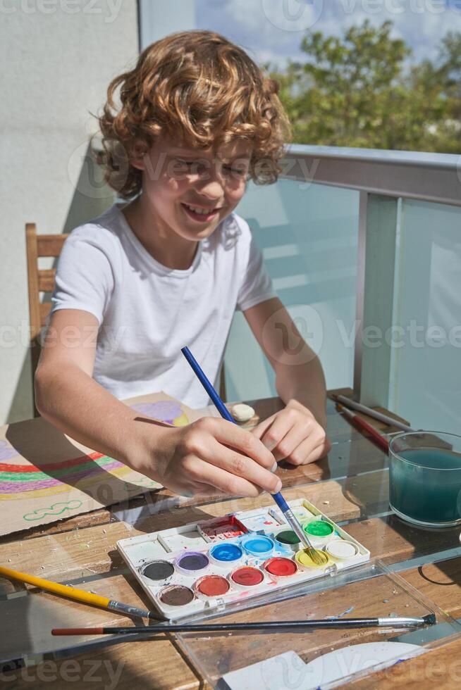 Smiling kid painting with watercolor paints photo