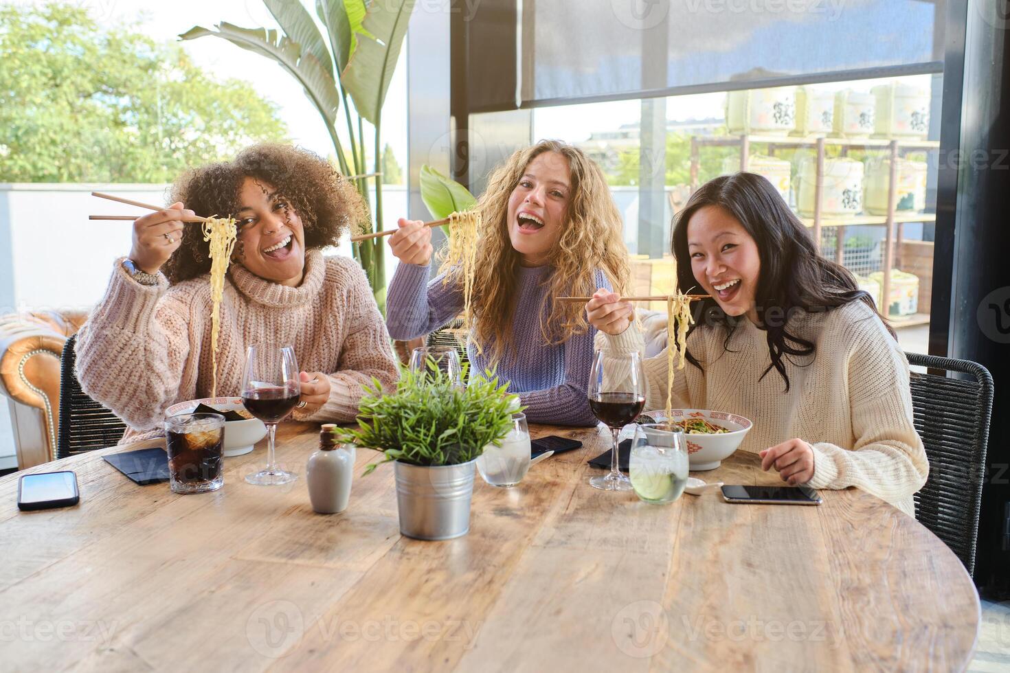 Delightful diverse female friends enjoying lunch in restaurant photo