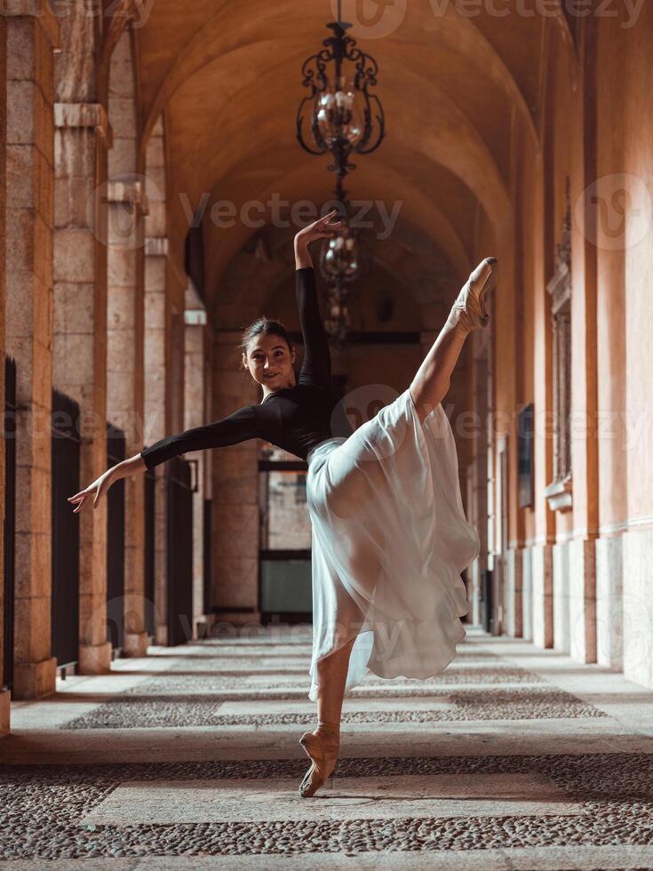 Graceful ballerina stretching raised forward leg in archway photo