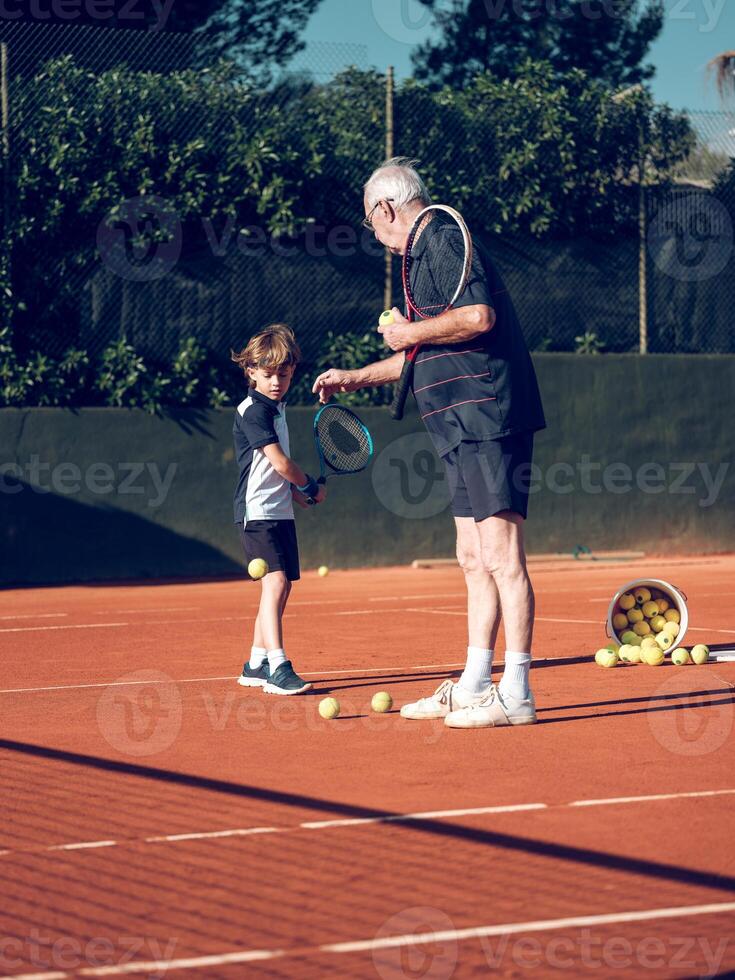 Senior trainer explaining preteen boy with tennis racket techniq photo