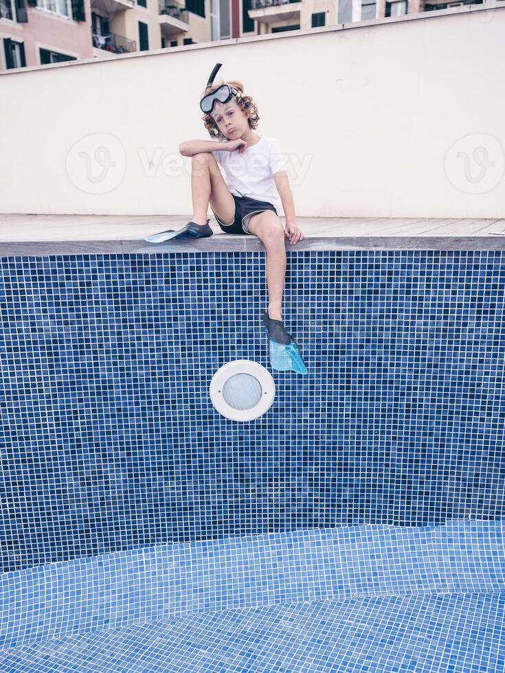 Puzzled boy in diving mask and flippers over empty pool photo